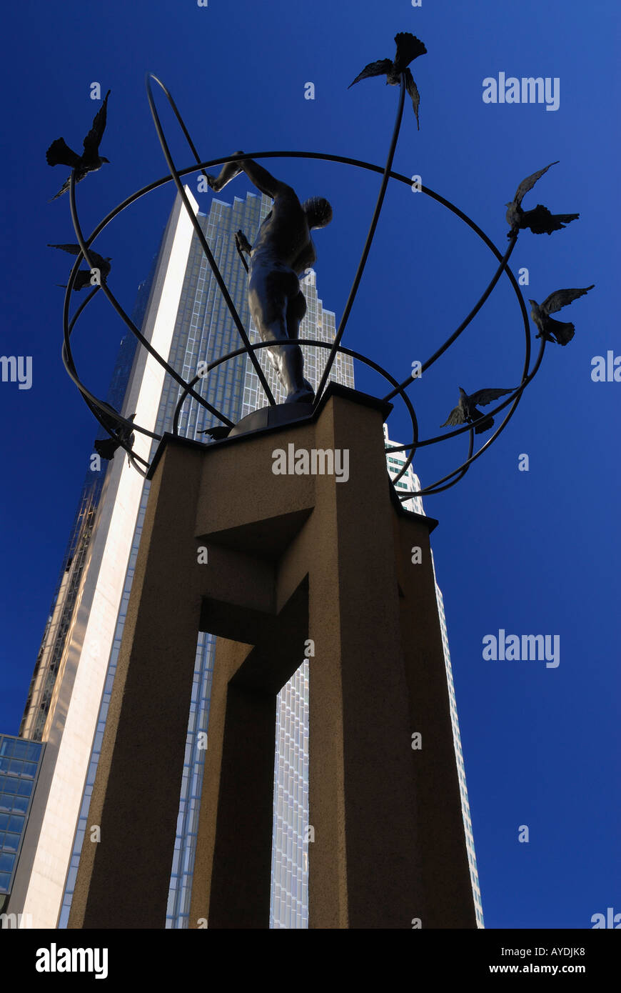 Toronto sculpture of man building a peaceful world with doves and gold bank tower on dark blue sky Stock Photo