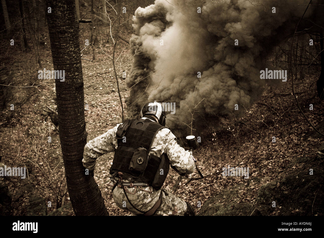 An anti-terrorist soldier during a training. A big cloud of dark smoke from a smoke grenade in a little distance. Stock Photo
