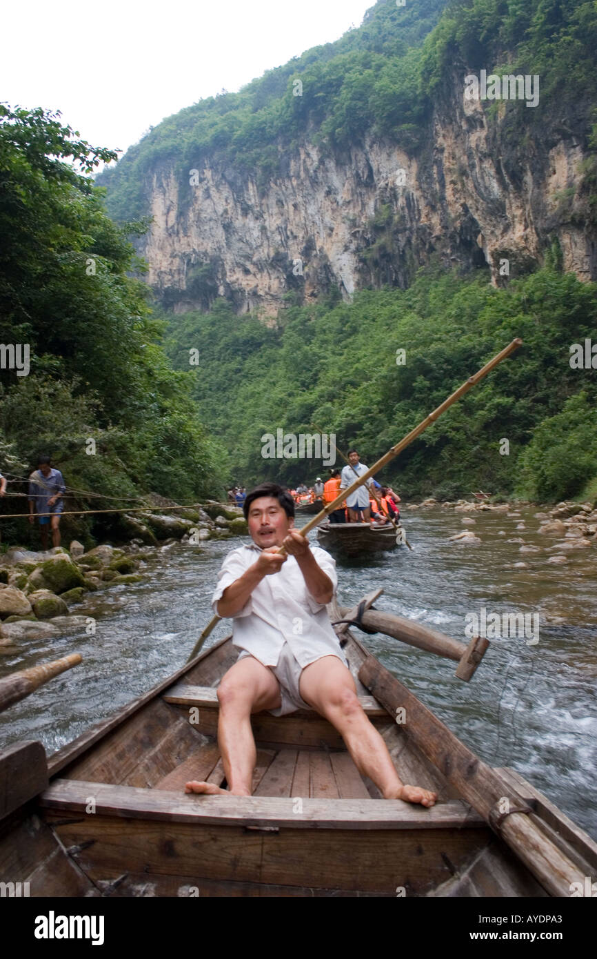 Chinese peapod boat fisherman strains against his bamboo cane pole