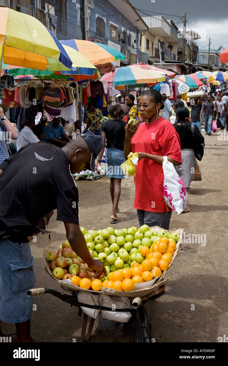 African Gabonese woman buying apples from a street hawker, Mont-Bouet Market, largest market in Libreville, Gabon Stock Photo