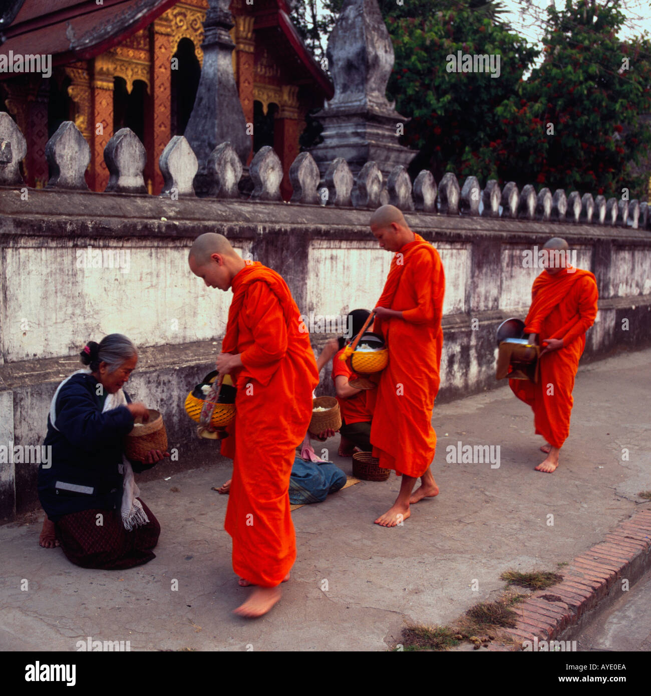 Laos Luang Prabang 3 monks on daily alms in front of Wat Saen temple Stock Photo