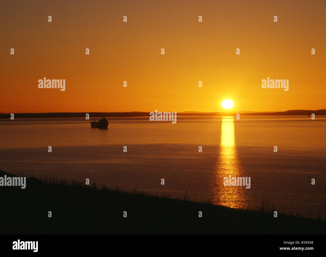 dh Sunset SCAPA FLOW ORKNEY Oil tanker and sunset over Flotta and Hoy orange sun north sea Stock Photo