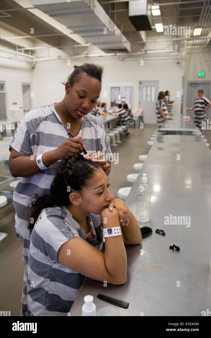 One female inmate works on another s hair in an indoor room at the Maricopa County tent jail Stock Photo