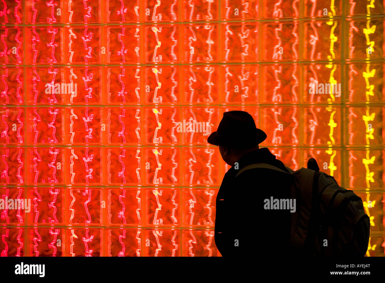Man walking past a glass block wall lit with red light at Washington Dulles International Airport Washington D C Stock Photo