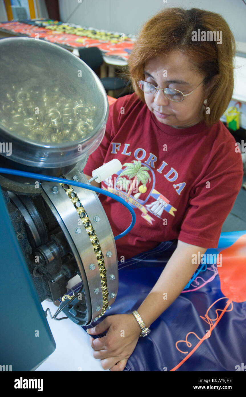 Woman Operating Machine Inserting Grommets In Banners Stock Photo