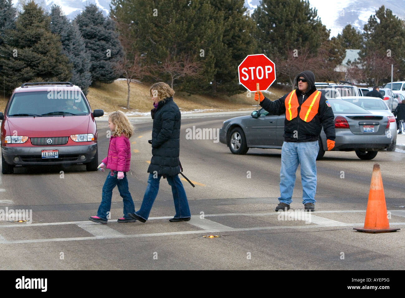 School crossing guard stops traffic to allow children and parents to cross the street in Boise Idaho Stock Photo