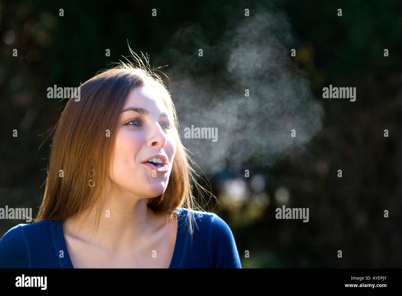 Young woman exhaling in the cold winter air Stock Photo Alamy