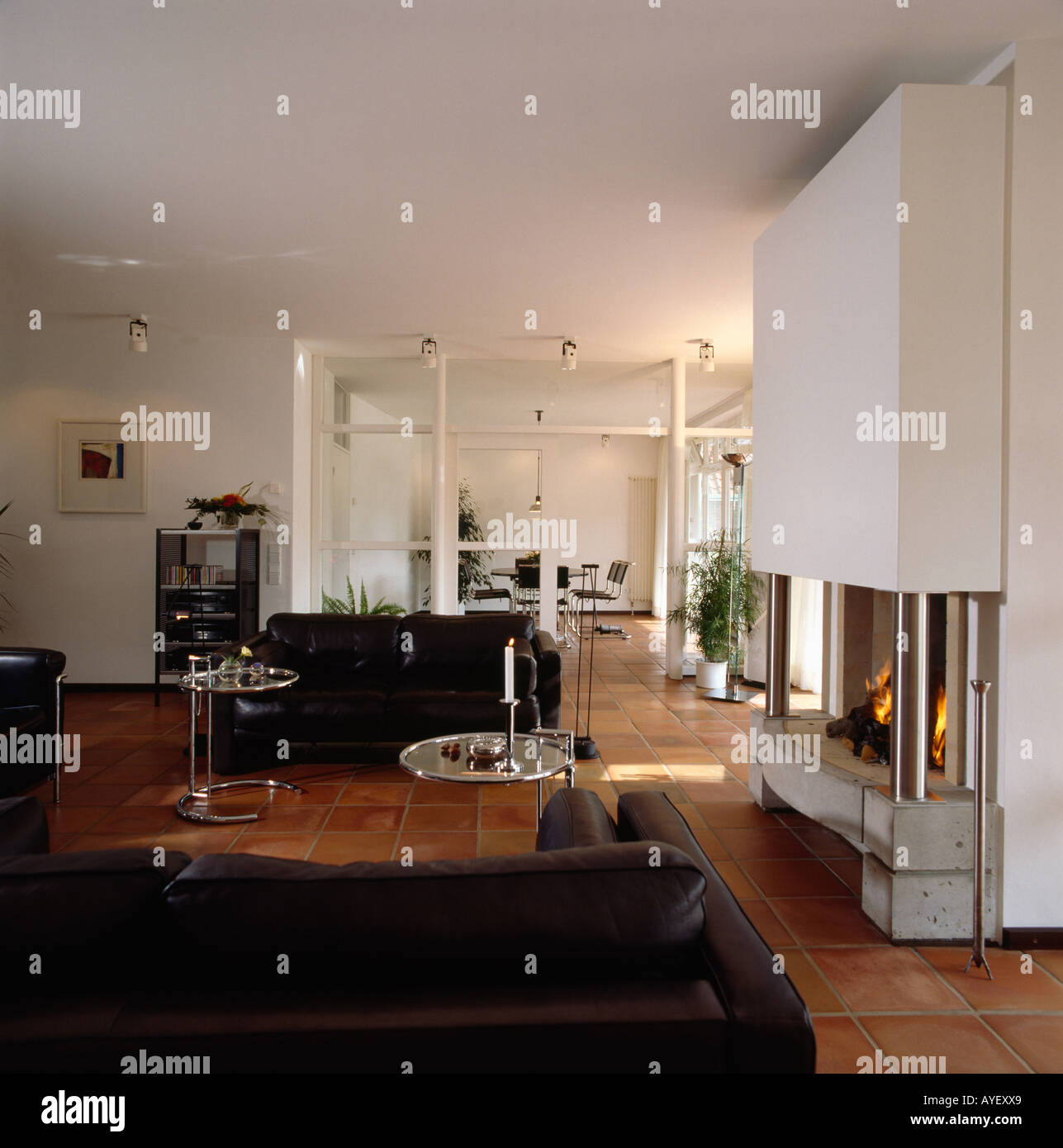 Large fireplace in modern white livingroom with black sofas Stock Photo