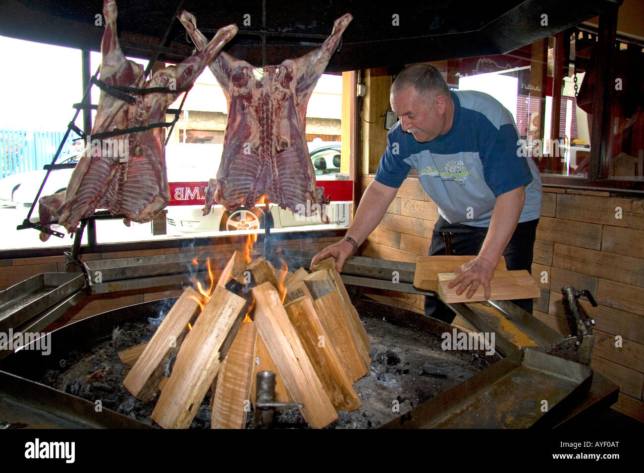 Man cooking lamb meat over an open fire in a restaurant at Ushuaia on the island of Tierra del