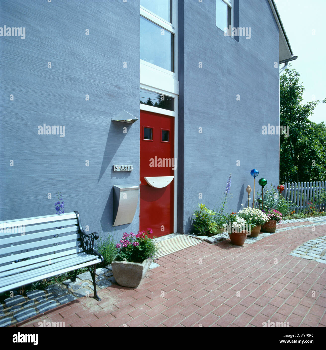 Modern Grey House With Red Front Door And Bench On Brick