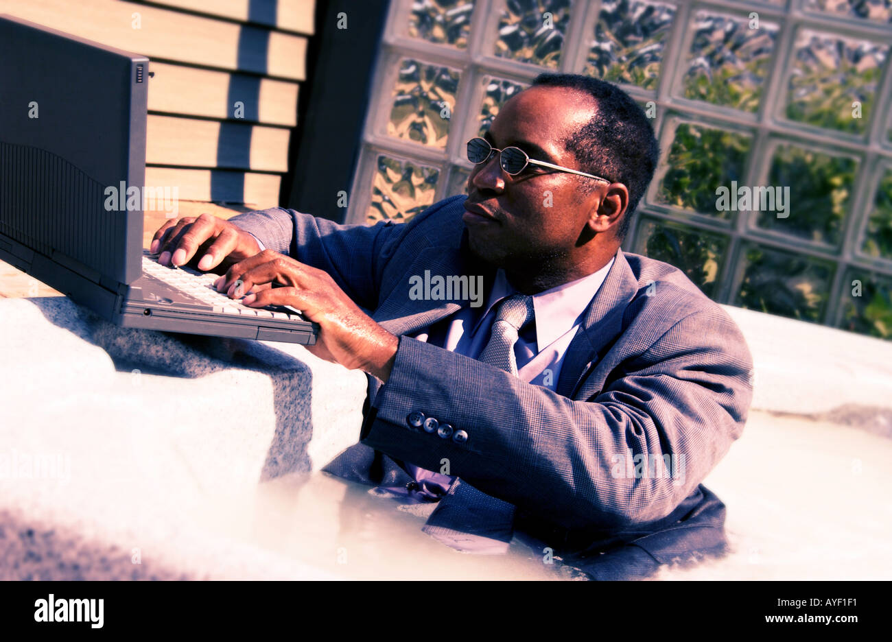Businessman on laptop in a hot tub Stock Photo Alamy