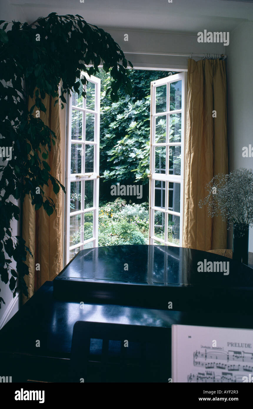 Grand Piano In Front Of Open Glass Doors To Garden Stock Photo