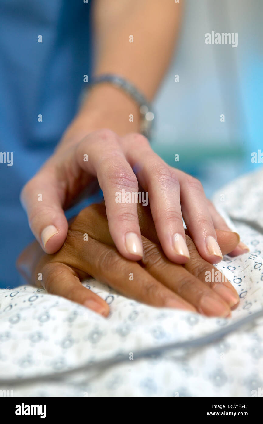 Caucasian female nurse s hand resting on african american female patient s hand Nurse s blue