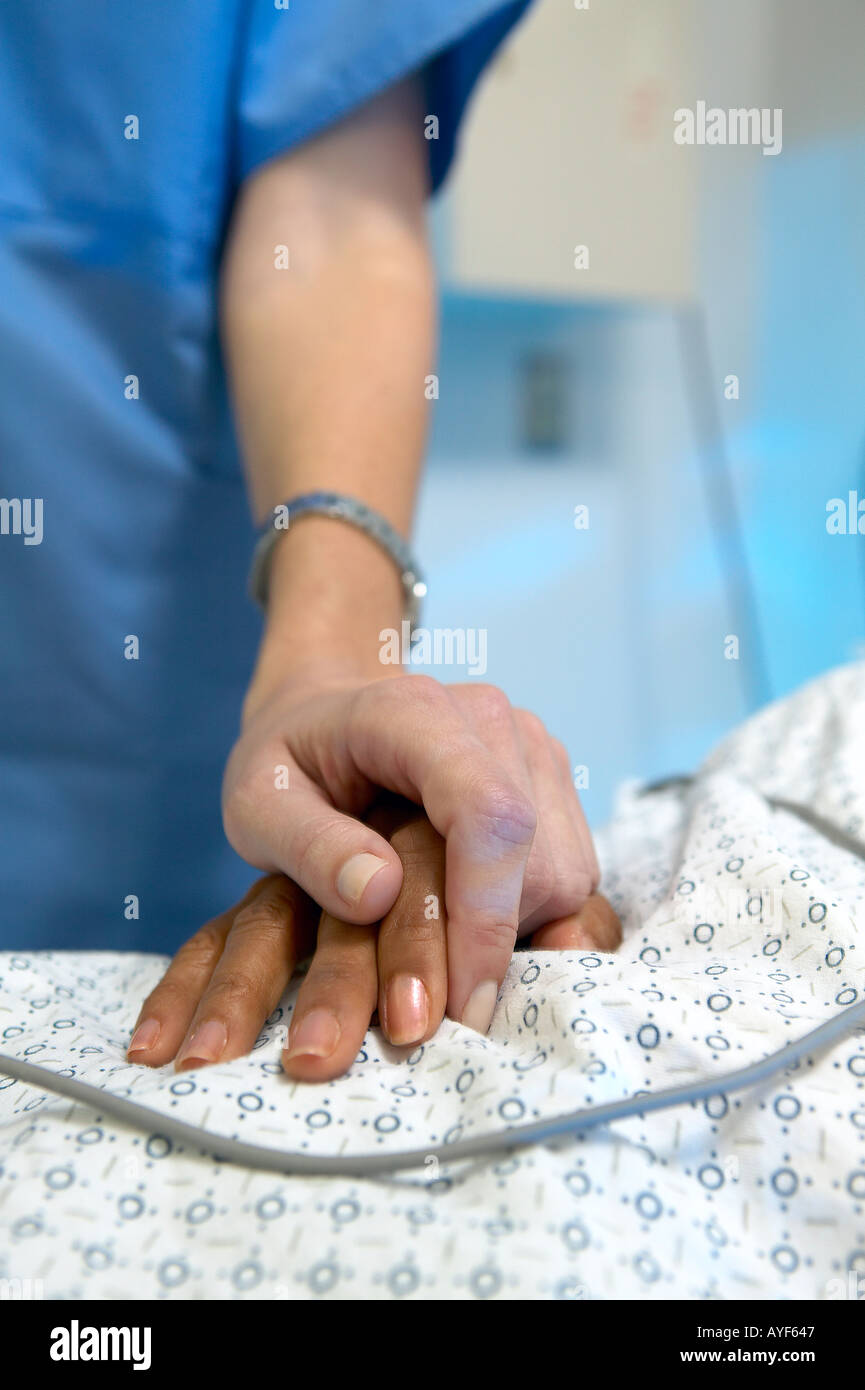 Caucasian female nurse s hand resting on african american female patient s hand Nurse s blue