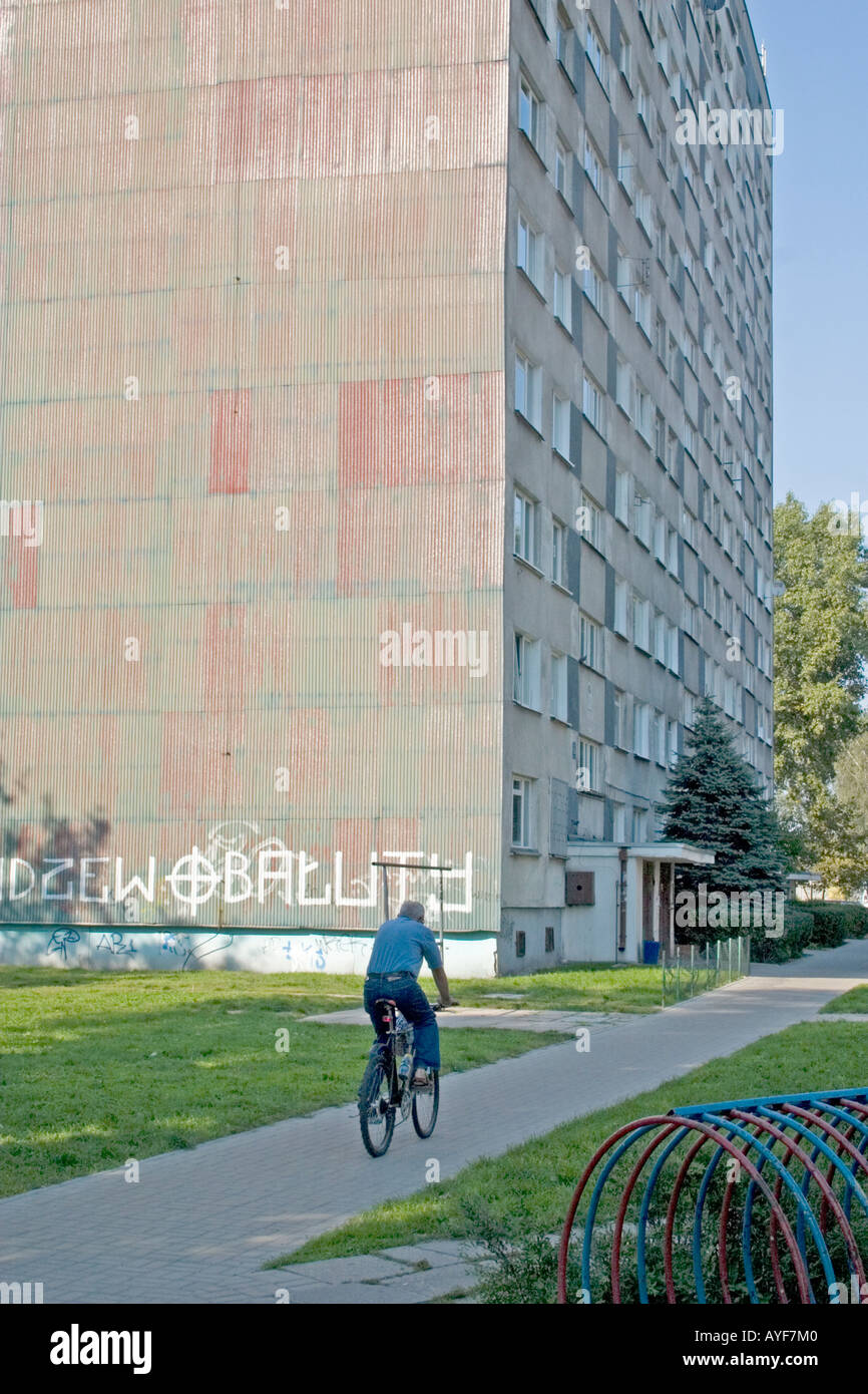 Bicycler traveling by Bloc housing a painful reminder of the Communist era. Lodz Central Poland Stock Photo