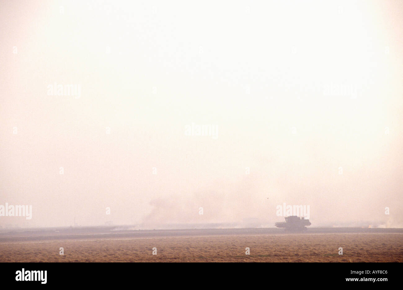 Rice harvester in the Donana area against backdrop of burning fields Andalusia Spain Stock Photo