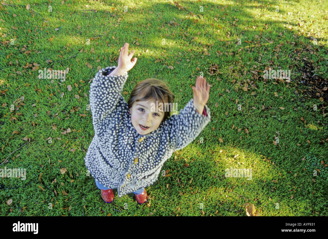 small girl looking up with arms raised Stock Photo