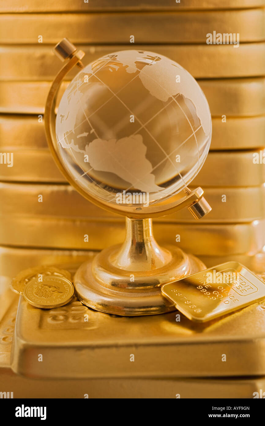 Globe in front of stack of gold bars Stock Photo