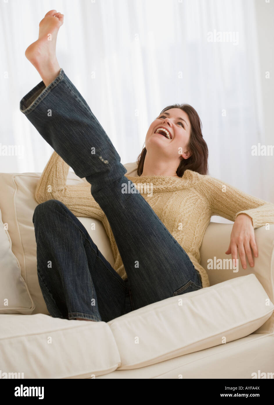 Woman kicking leg on sofa Stock Photo