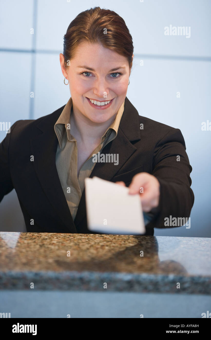 Customer service representative handing ticket over counter Stock Photo