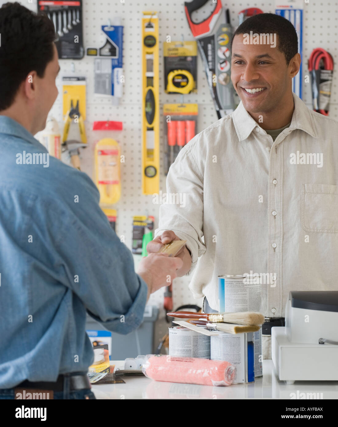 African sales clerk at hardware store handing over credit card Stock