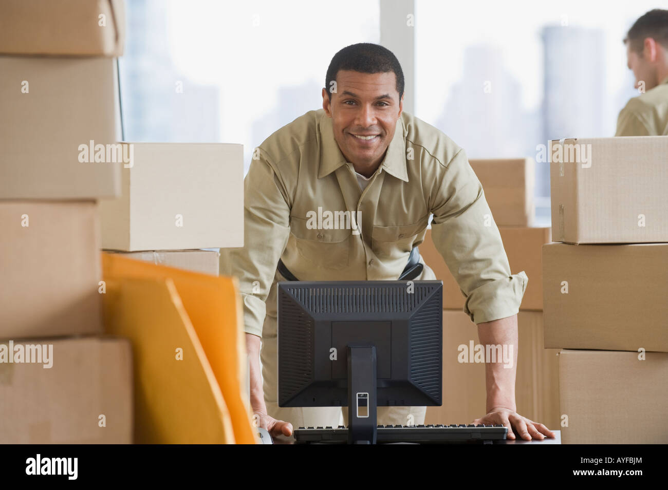 African delivery man next to computer Stock Photo