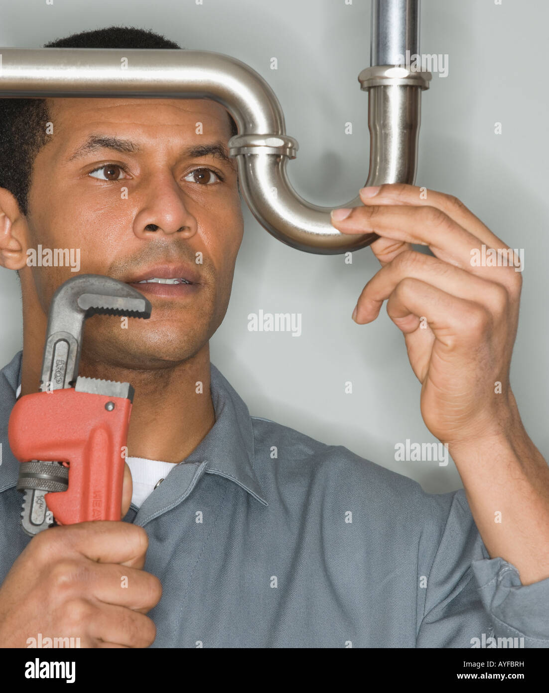 African male plumber holding wrench next to pipe Stock Photo Alamy