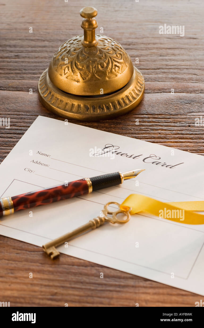 Guest registry card, pen, key and bell on table Stock Photo