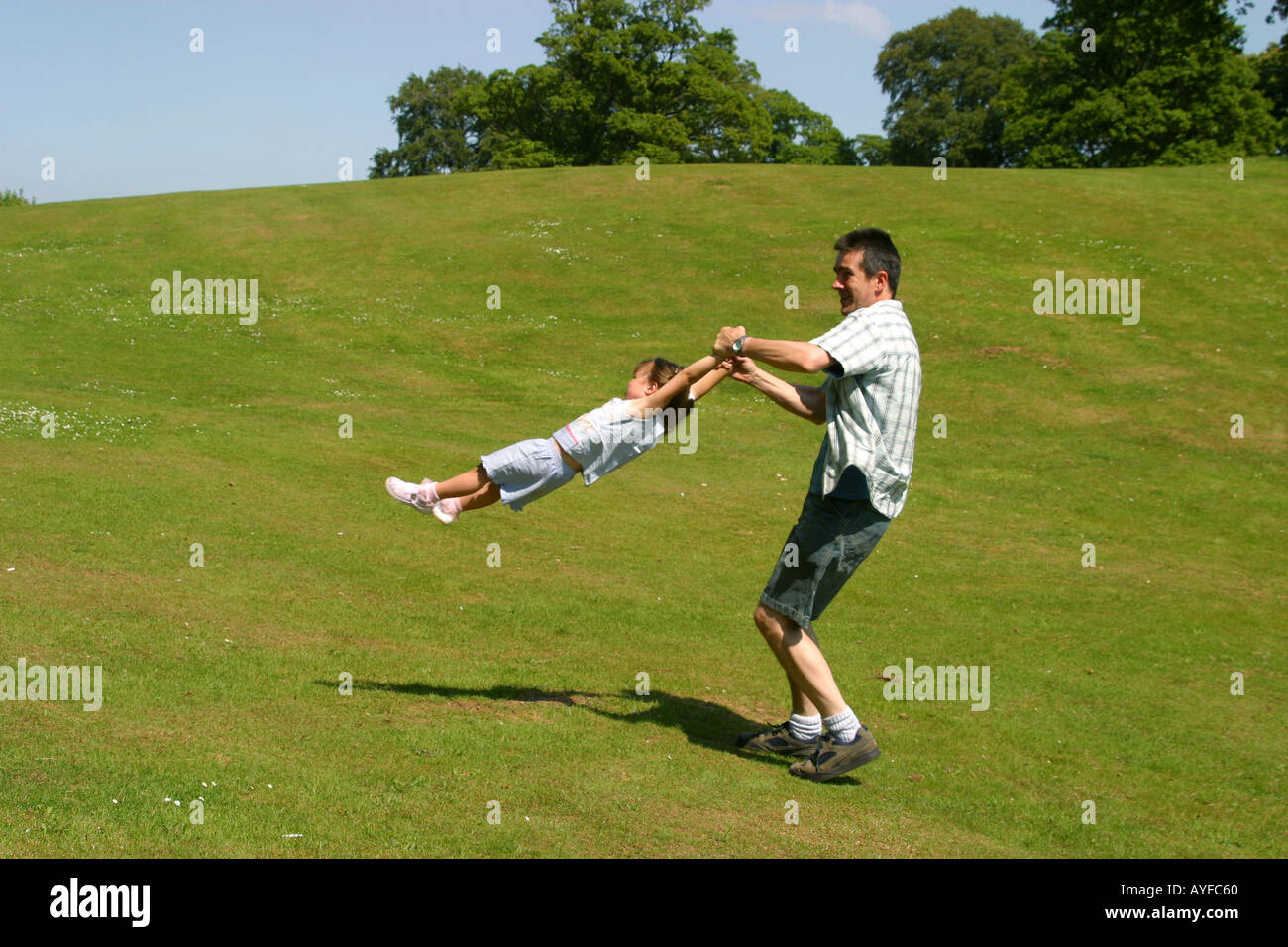 Father spinning young daughter around by her arms Stock Photo