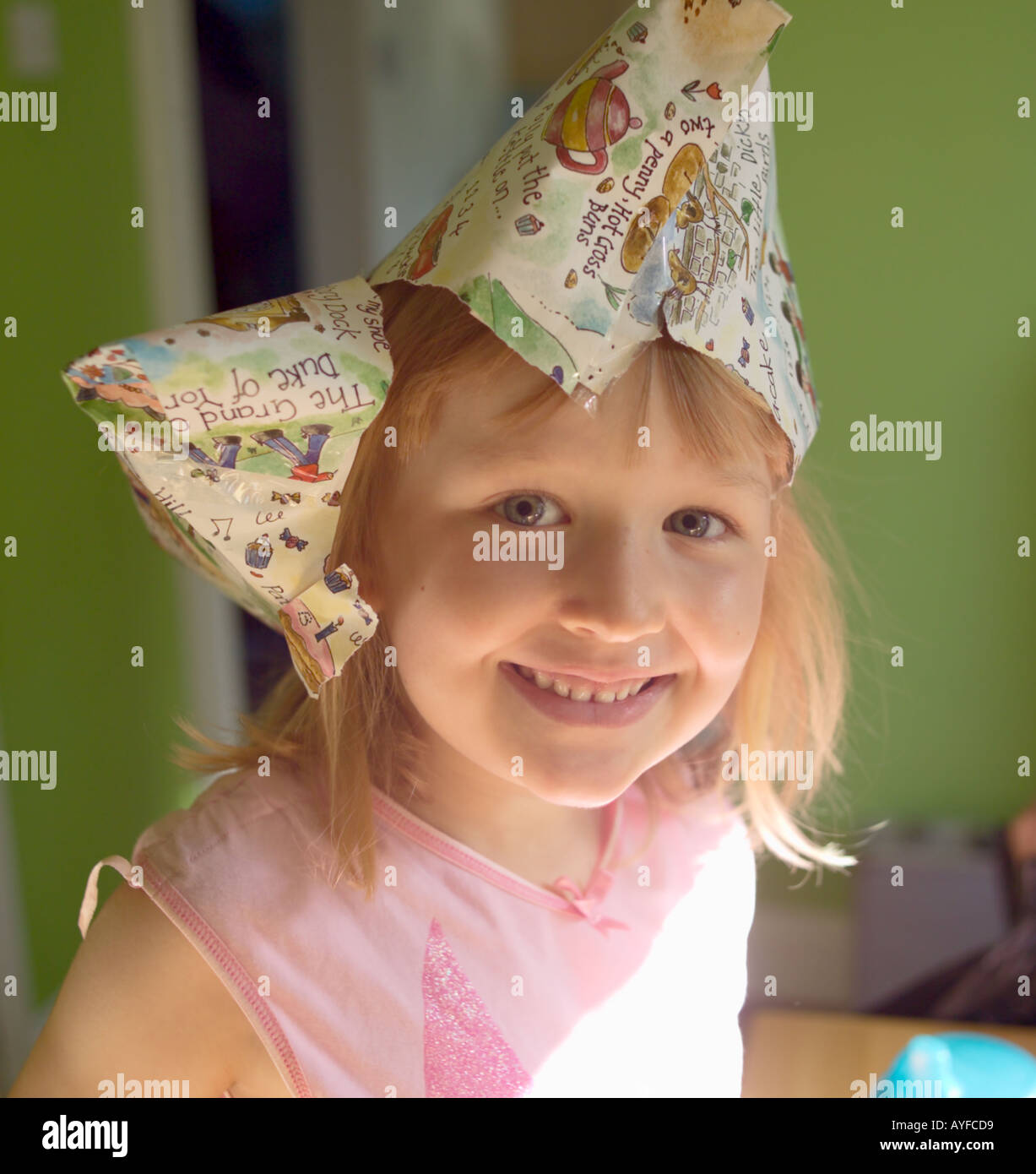 Five year old girl on her birthday with a hat made out her present s wrapping paper on her head Stock Photo