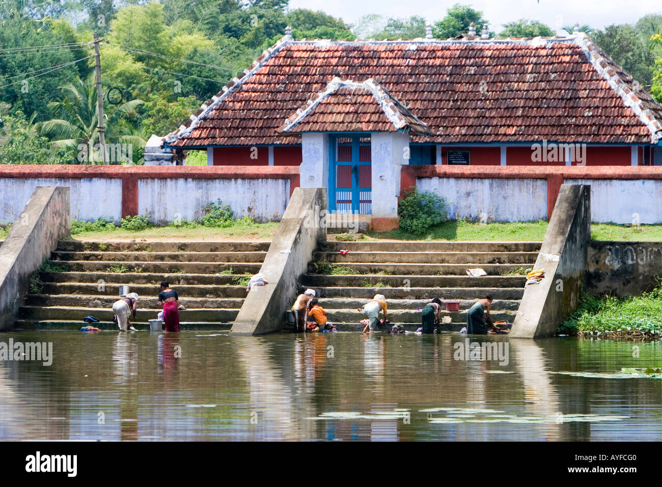 Kerala women washing clothes on the steps of a building by a lake