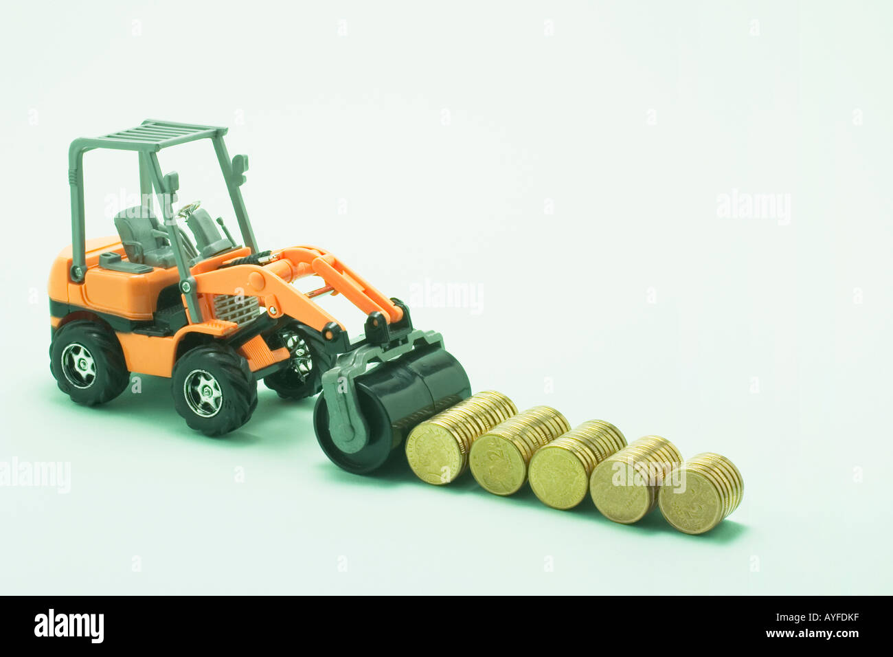 Miniature Road Roller with Rolls of Coins Stock Photo