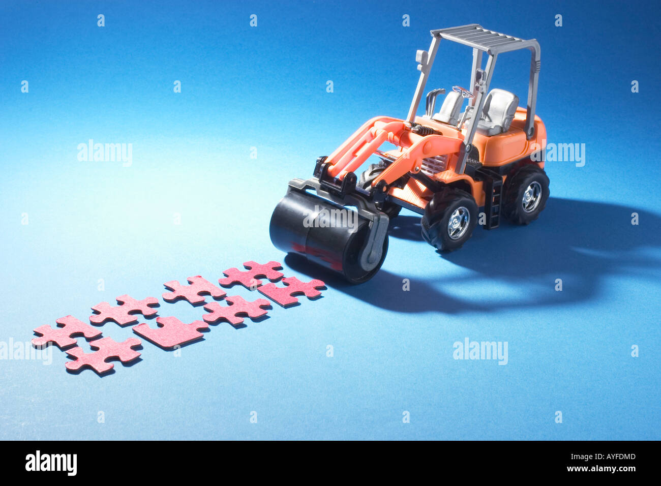 Miniature Road Roller and Jigsaw Puzzle Pieces Stock Photo