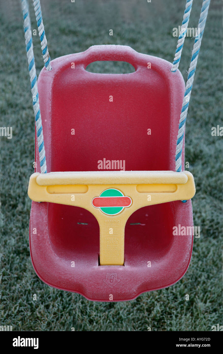 childs red swing seat idle in the early morming frost Stock Photo
