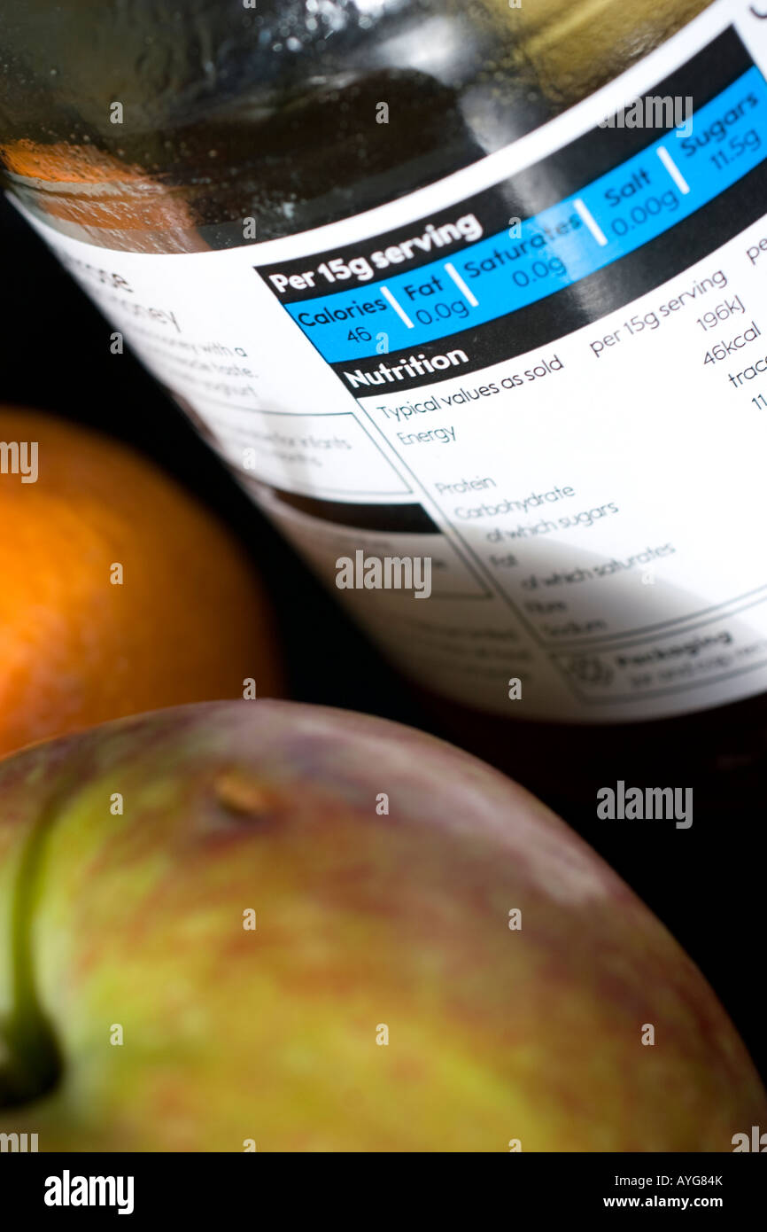 food ingredients labels labeling on jar of honey with fresh fruit in background displaying nutrional information Stock Photo