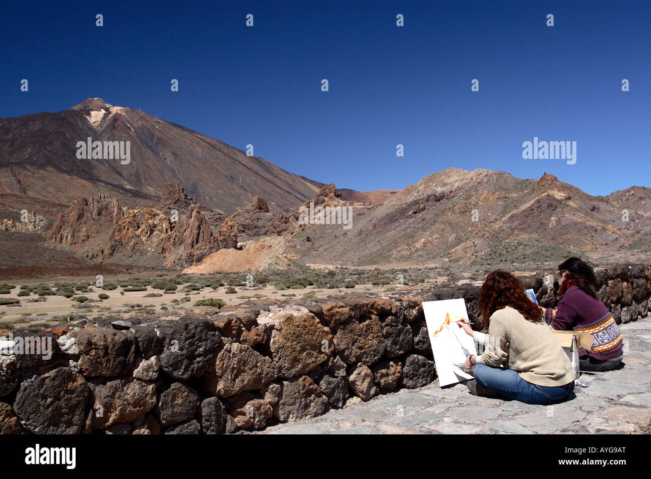 Two women painting the dormant volcano of Mount Teide and the surrounding volcanic landscape on Tenerife in the Canary Island Stock Photo