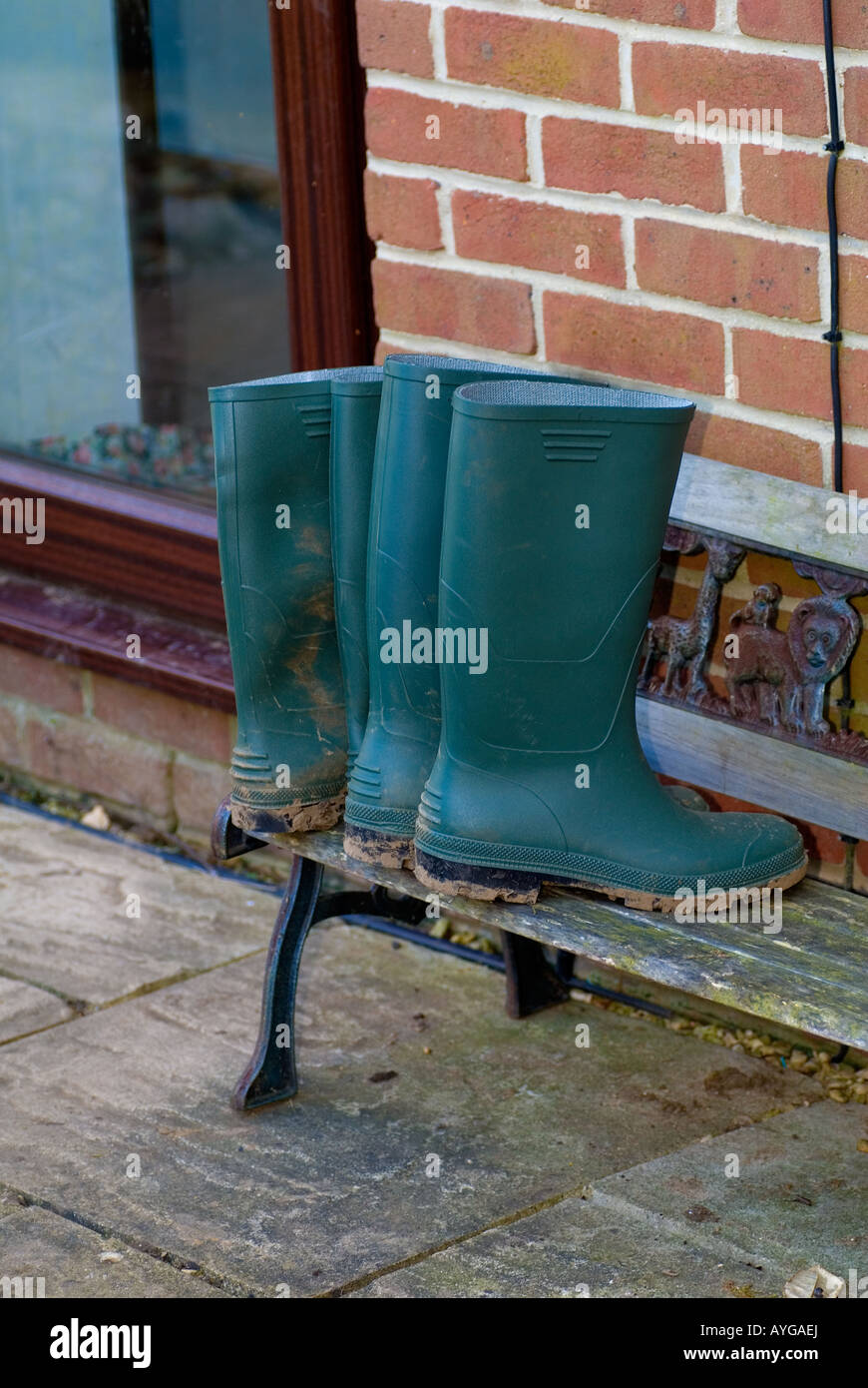 Two Pairs of Green Wellington Boots on a small Childs Bench Stock Photo