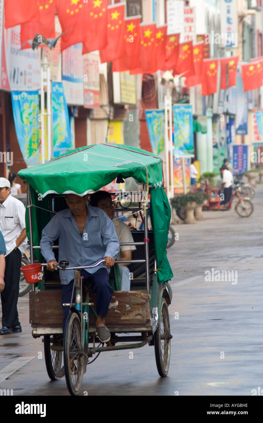 Chinese Flag Lined Street Scene A bicycle taxi cart riding along ...