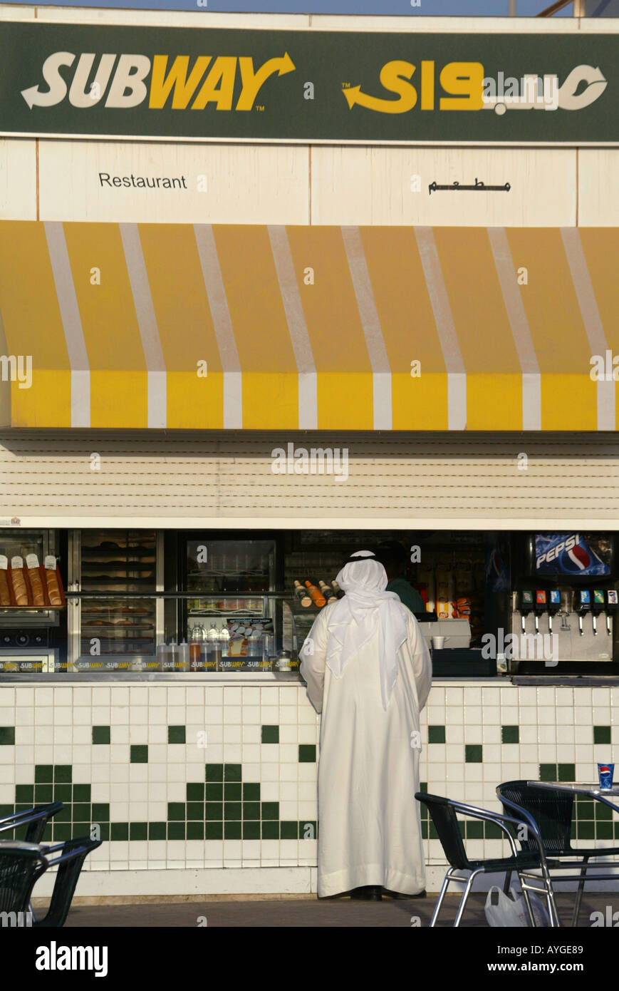 A Kuwati man in thaub traditional clothing orders at a Subway fast food restaurant along the Sharq Pier in Kuwait City. Stock Photo