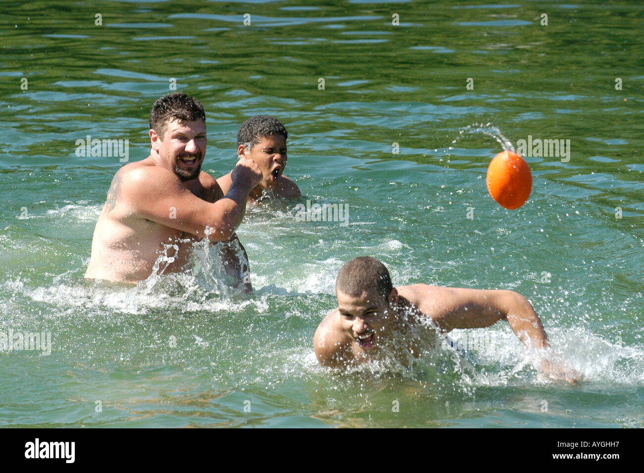 3 boys play with football in the water Stock Photo