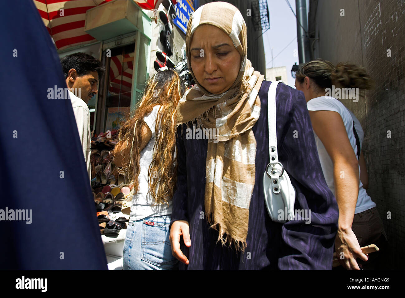 Woman in traditional clothes makes her way down bustling narrow lane Medina Tunis Tunisia Stock Photo