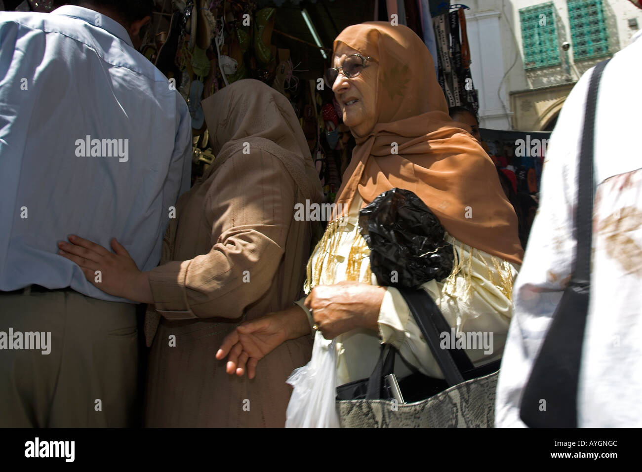 Woman in traditional clothes shopping in narrow lane Medina Tunis Tunisia Stock Photo