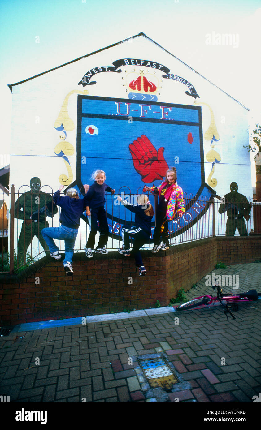 Street kids playing .Loyalist Murals on the streets of Shankhill Rd depicting the paramilitary struggles, West Belfast Stock Photo