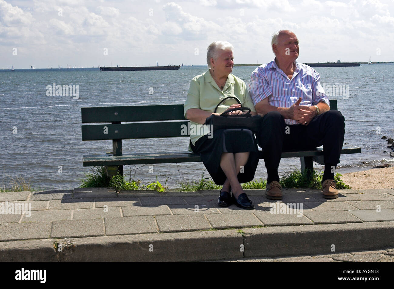 Elderly couple rest on seaside bench Volendam fishing village The Netherlands Stock Photo