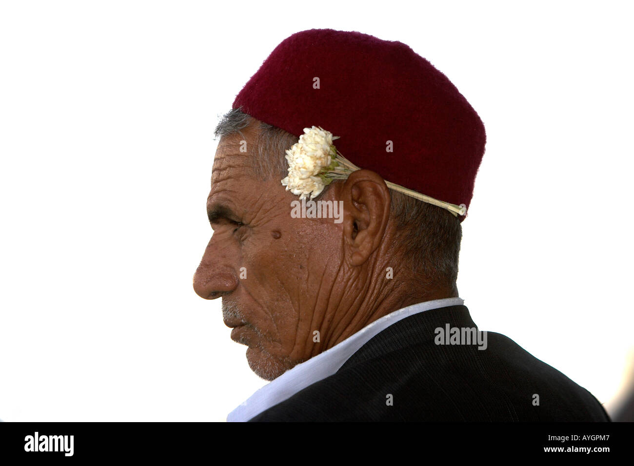 Jasmine seller in skull cap wears white blossom behind ear outside Sousse Medina Tunisia Stock Photo