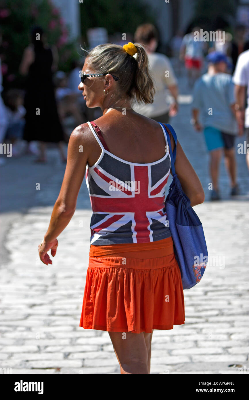 Woman in Union Jack flag top and orange mini skirt strolls round Kantaoui Marina Tunisia Stock Photo