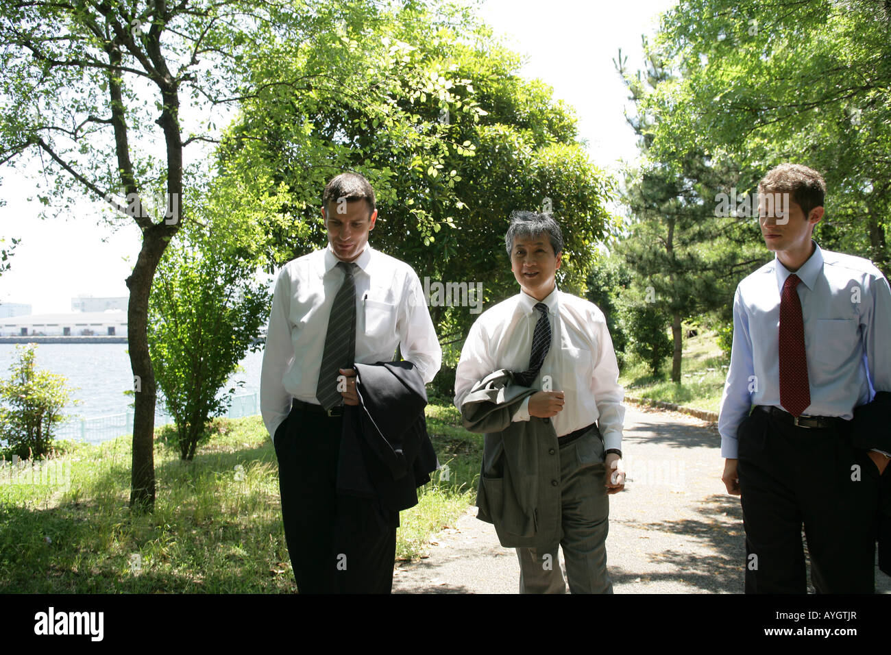 Three business men walking along park path Stock Photo - Alamy