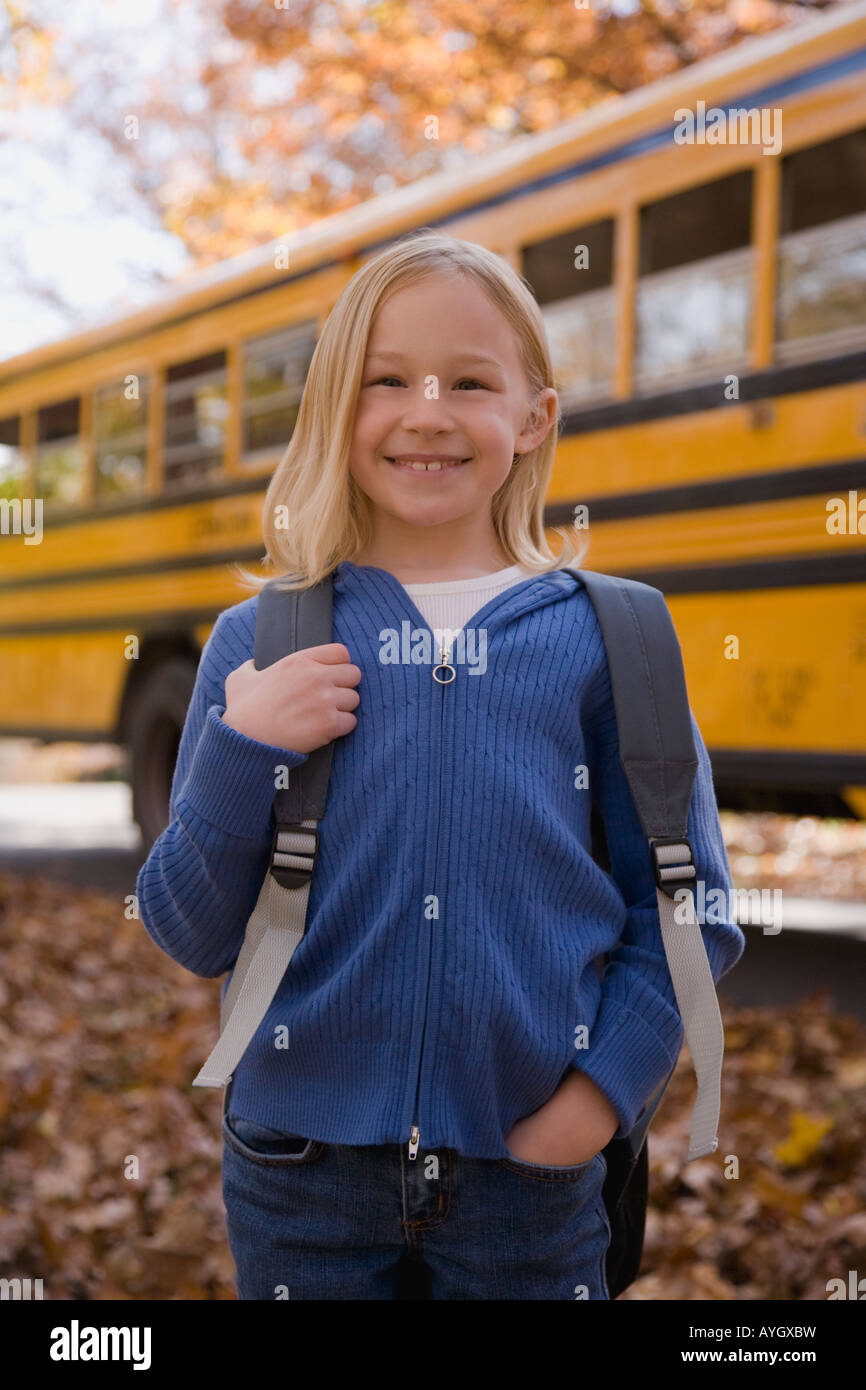 Girl with backpack in front of school bus Stock Photo Alamy