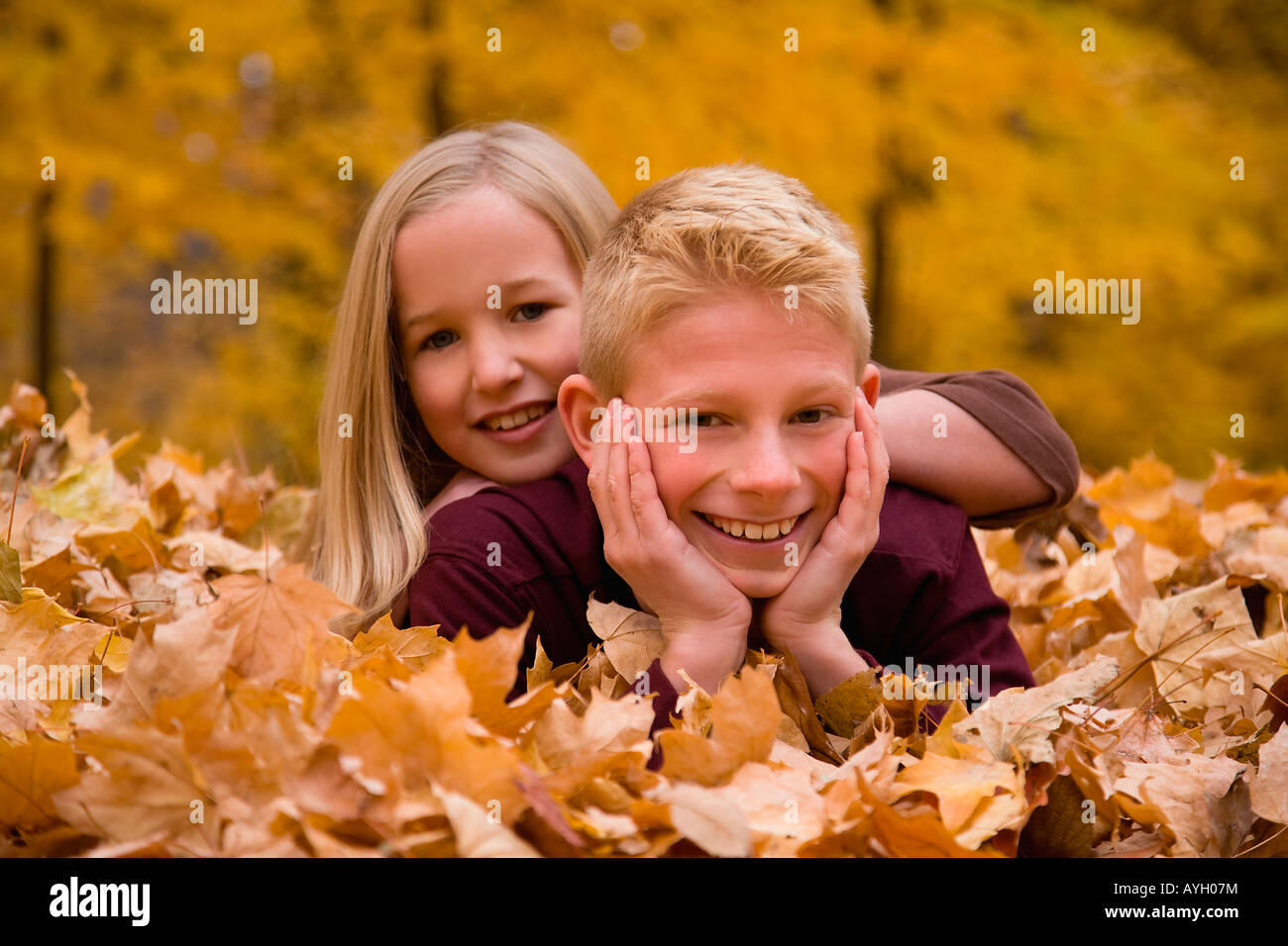 Sister and brother laying in autumn leaves Stock Photo - Alamy