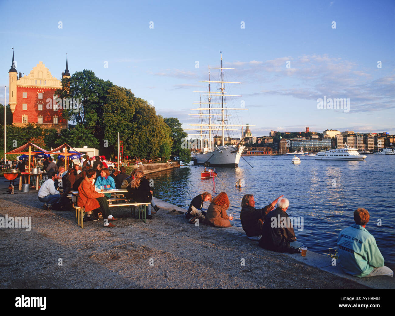 People eating and drinking at Skeppsholmen Island in Stockholm at sunset near Af Chapman schooner Stock Photo